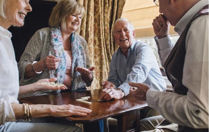 Four seniors gathered around a table playing a game