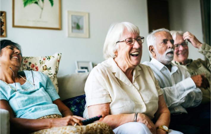 A group of residents sitting and laughing while watching TV.