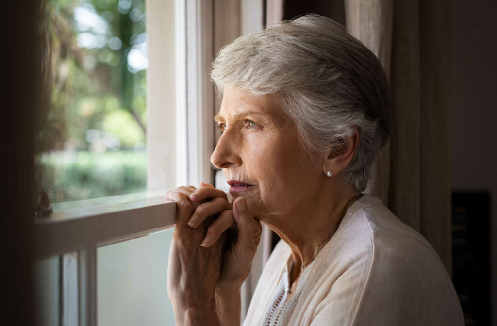 A depressed elderly woman looking out the window.
