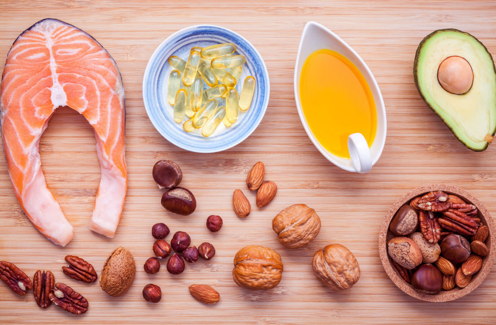 Selection food sources of omega 3 and unsaturated fats. Superfood high vitamin E for  maintaining healthy memory. Almond ,pecan , hazelnuts, walnuts ,olive oil ,fish oil ,avocado and salmon on bamboo cutting board.
