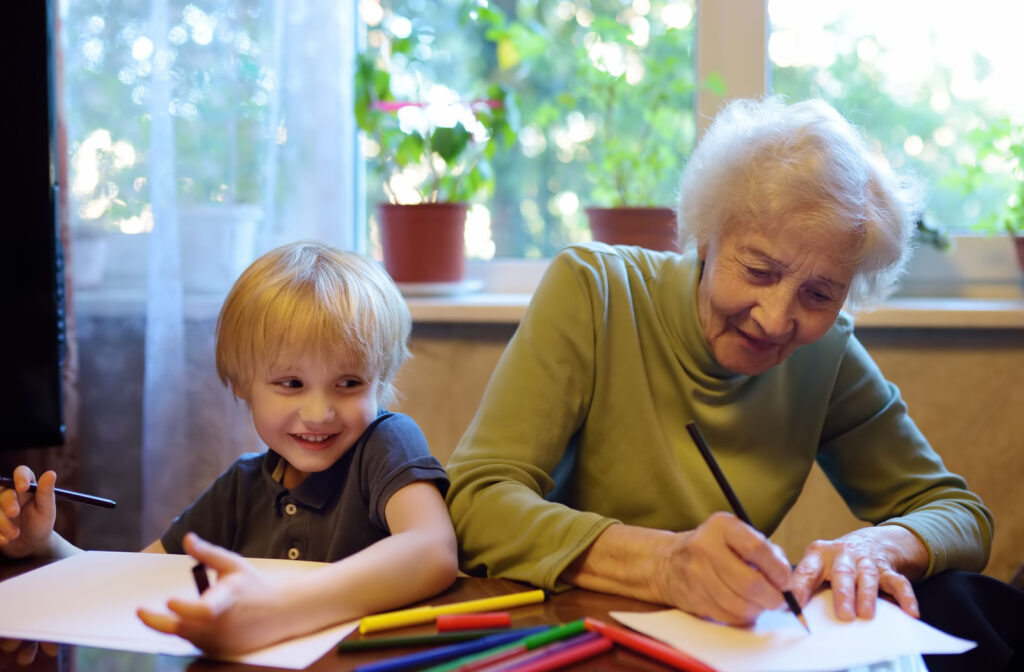 A senior woman teaching a young child how to draw.