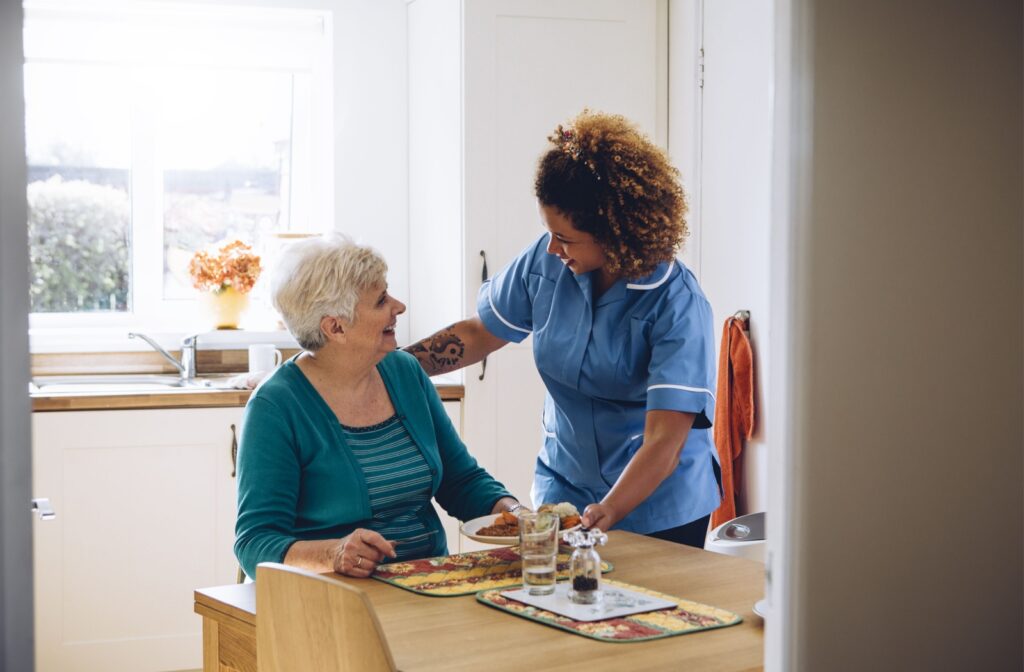 An assisted living staff serving food to a resident.