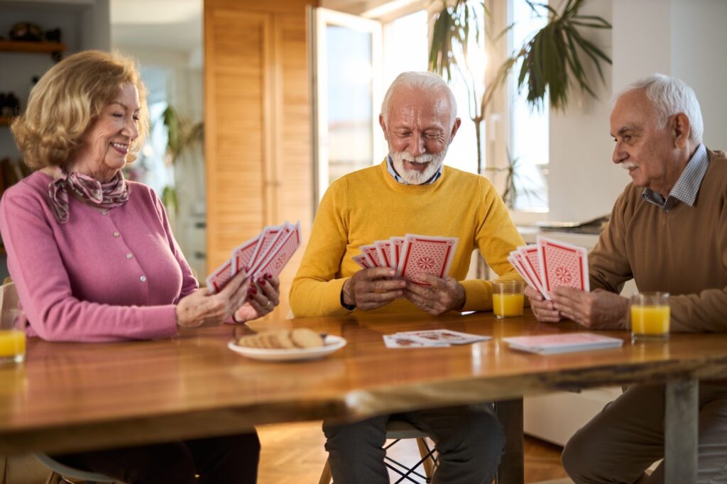 Three seniors playing cards around a table.