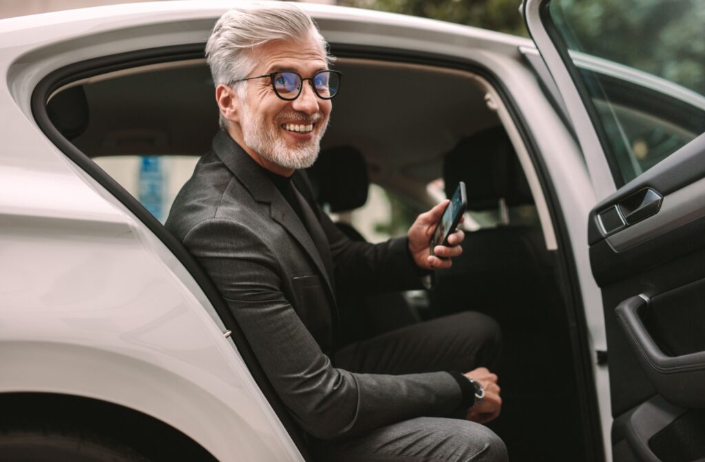 A smiling person steps out of a rideshare vehicle.