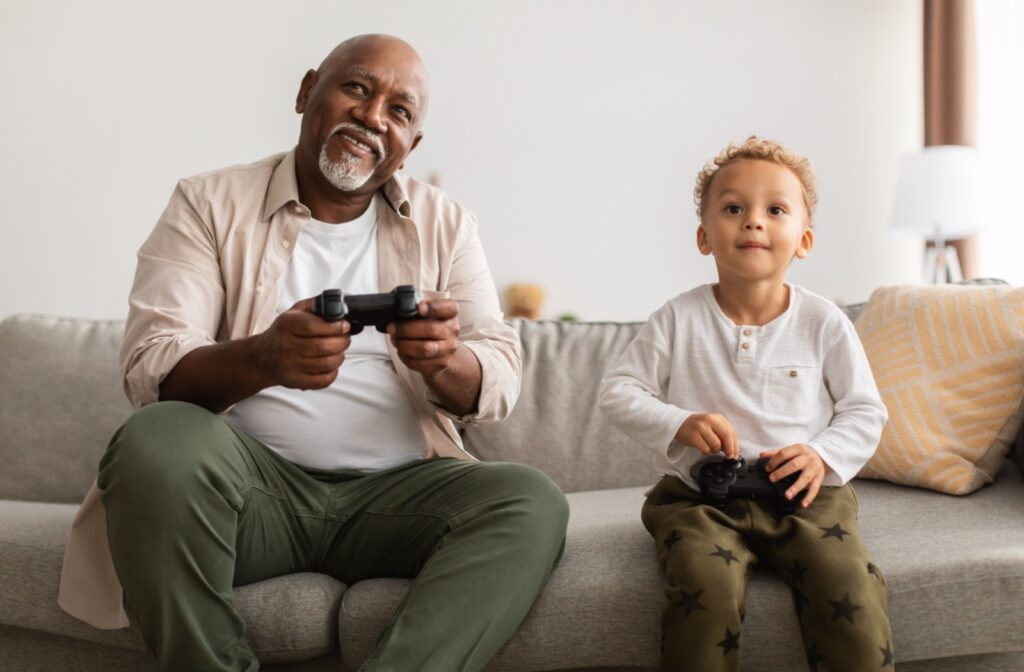 A grandparent and grandchild play video games on the couch together.