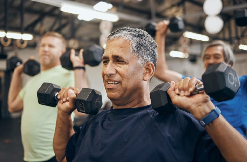 Three seniors lift dumbbell weights together as part of group fitness classes offered by their independent living community