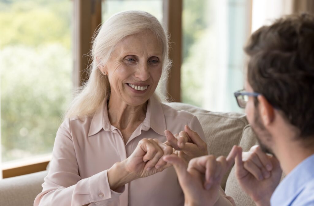 A senior uses sign language to communicate with their family member in memory care.
