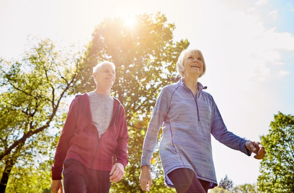 Two senior retirees enjoy a brisk outdoor walk on a sunny day