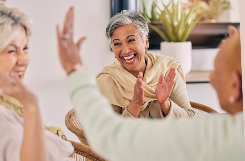 A group of senior friends clap, high-five, and laugh together.